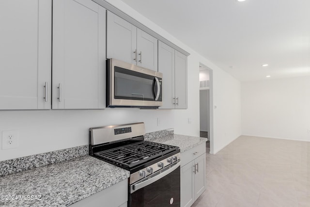 kitchen with light tile patterned flooring, light stone counters, and appliances with stainless steel finishes