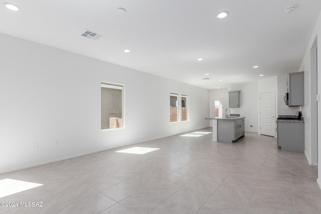 unfurnished living room with light tile patterned floors and sink