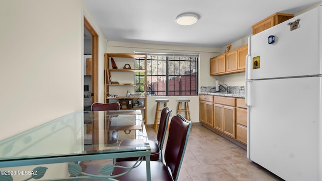 kitchen with white refrigerator, sink, and light brown cabinets