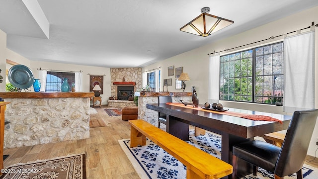 dining room with light hardwood / wood-style floors and a stone fireplace