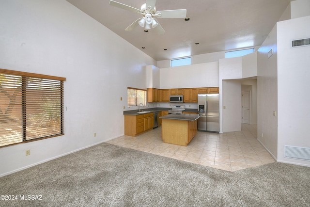 kitchen featuring light carpet, appliances with stainless steel finishes, a towering ceiling, sink, and a center island