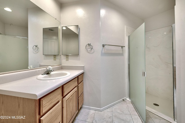 bathroom with a shower with door, vanity, and tile patterned flooring