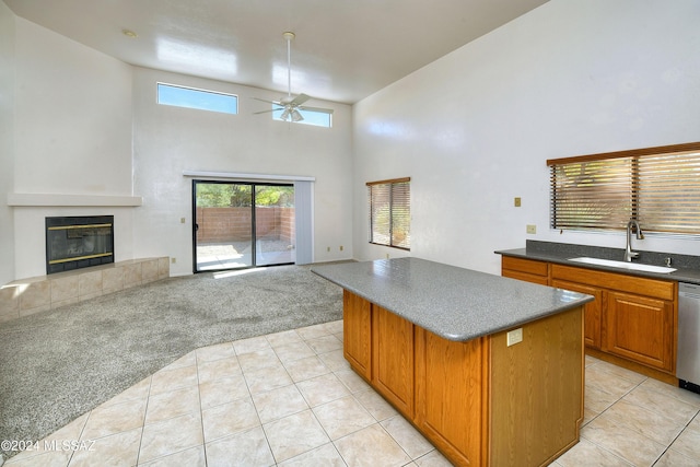 kitchen featuring a center island, a tile fireplace, sink, ceiling fan, and light colored carpet