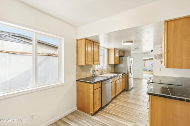 kitchen with tasteful backsplash, sink, stainless steel appliances, and light wood-type flooring