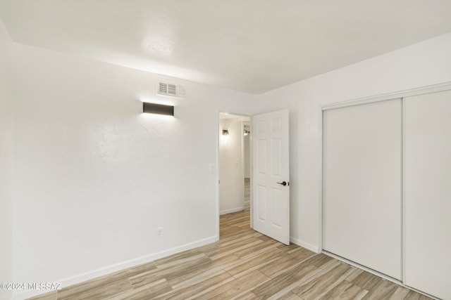 unfurnished bedroom with a closet and light wood-type flooring