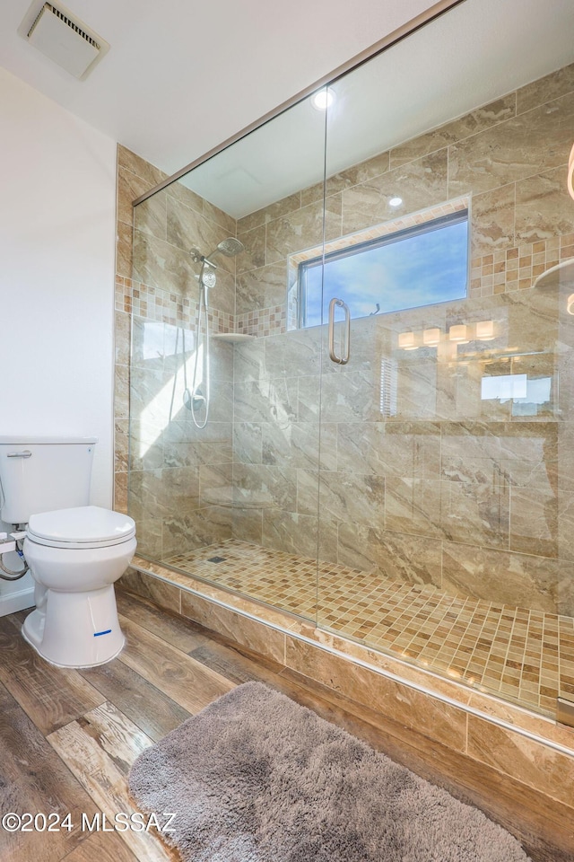 bathroom featuring hardwood / wood-style flooring, toilet, and a shower with door