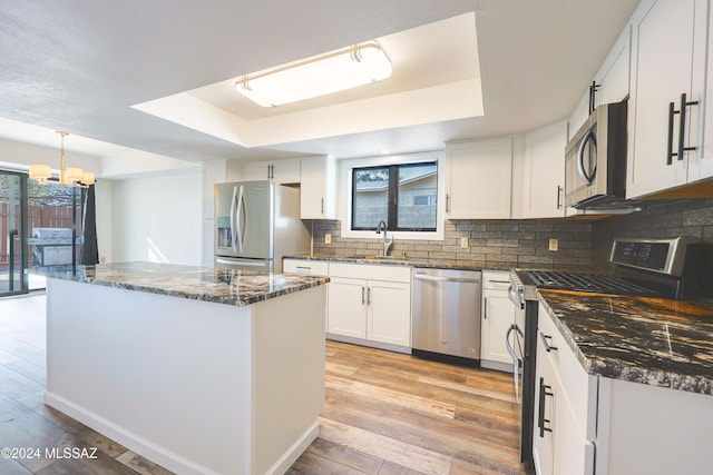 kitchen with a center island, stainless steel appliances, white cabinetry, and a wealth of natural light