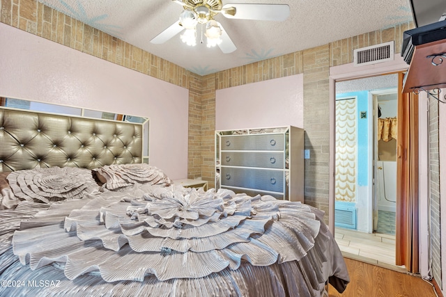 bedroom featuring ceiling fan, hardwood / wood-style flooring, and a textured ceiling