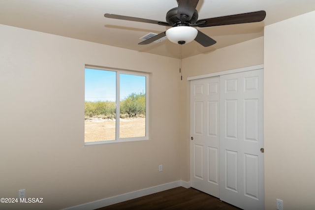 unfurnished bedroom with ceiling fan, a closet, and dark wood-type flooring