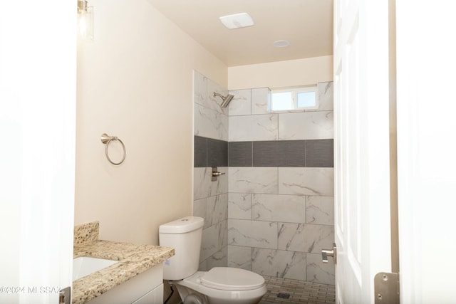 bathroom featuring tiled shower, vanity, and toilet