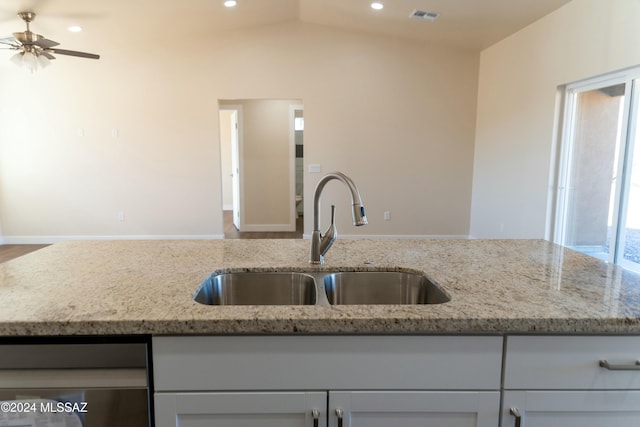 kitchen featuring light stone countertops, vaulted ceiling, ceiling fan, and sink