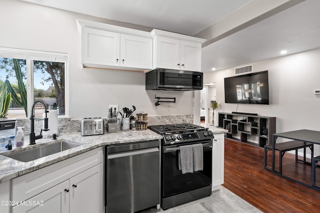 kitchen featuring appliances with stainless steel finishes, white cabinetry, sink, hardwood / wood-style flooring, and light stone countertops