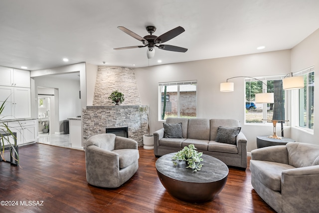 living room featuring dark hardwood / wood-style floors, ceiling fan, a fireplace, and a wealth of natural light