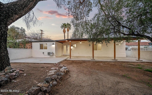 back house at dusk featuring a patio area