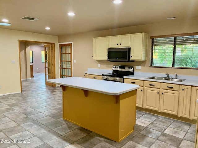 kitchen with a breakfast bar, a center island, stainless steel appliances, and sink