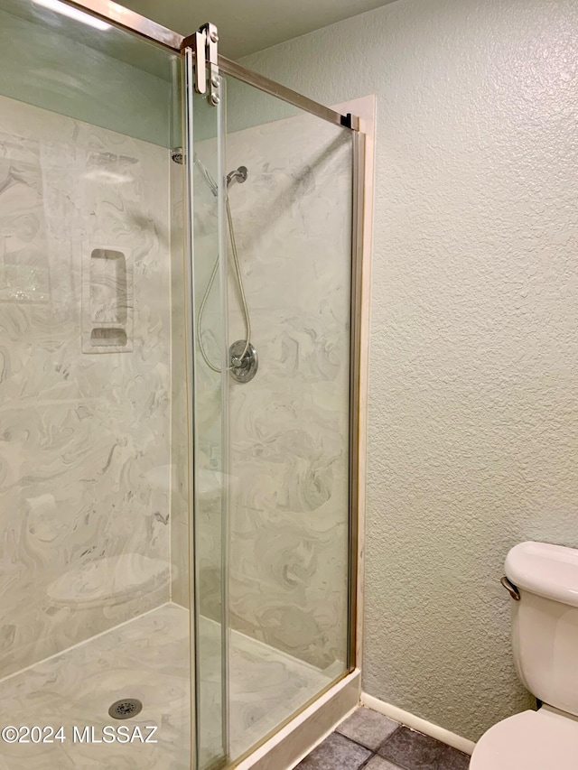 bathroom with toilet and a shower with shower door