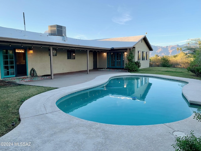 view of swimming pool featuring french doors, central AC unit, a mountain view, a yard, and a patio