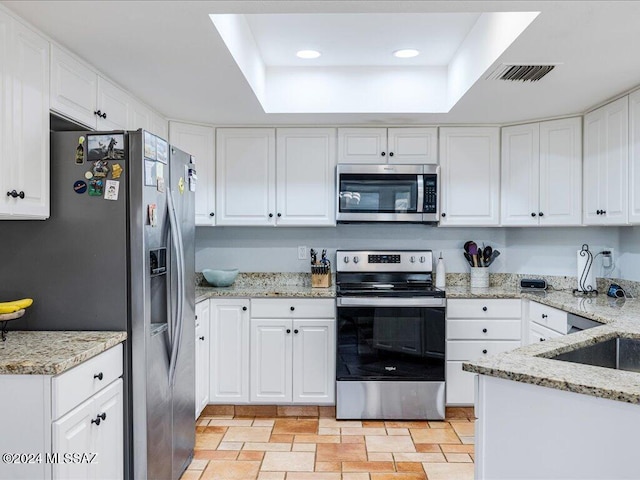 kitchen featuring visible vents, white cabinetry, stainless steel appliances, and light stone counters