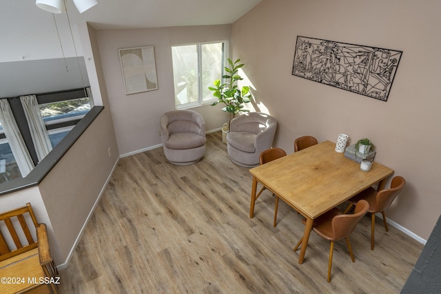 dining area featuring vaulted ceiling and light hardwood / wood-style flooring