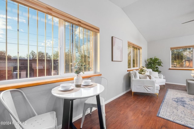 dining area with dark wood-type flooring and vaulted ceiling