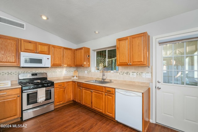 kitchen with lofted ceiling, white appliances, sink, decorative backsplash, and dark hardwood / wood-style flooring