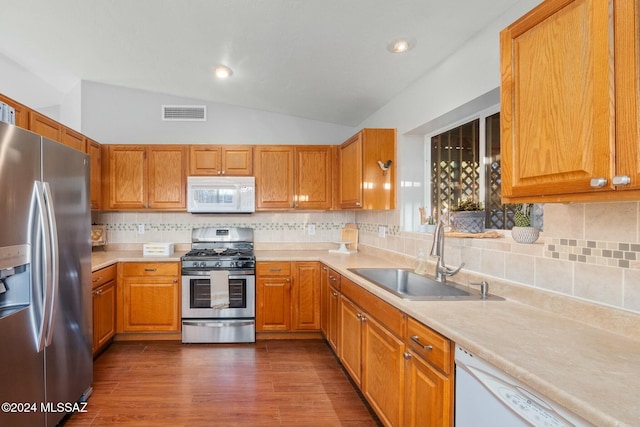 kitchen featuring decorative backsplash, stainless steel appliances, vaulted ceiling, sink, and dark hardwood / wood-style floors