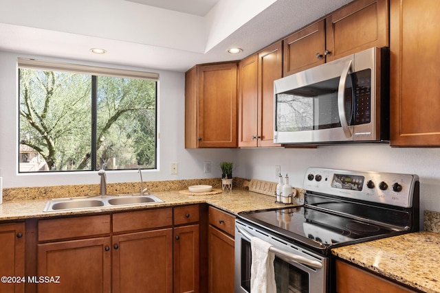 kitchen with light stone countertops, appliances with stainless steel finishes, and sink