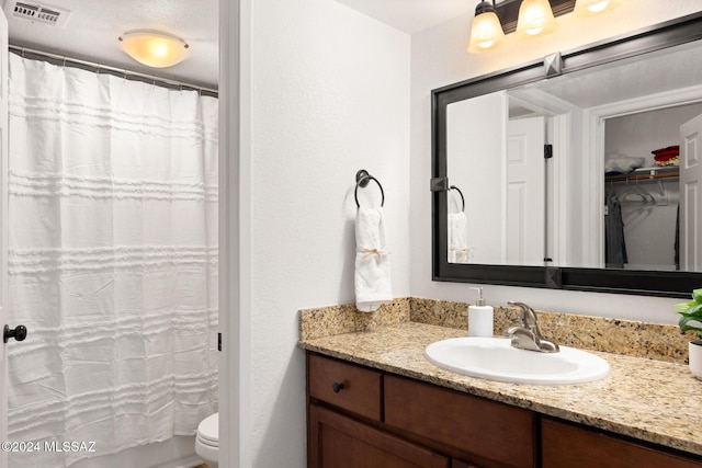 bathroom featuring a shower with shower curtain, vanity, and toilet