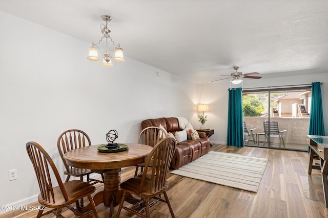 dining area featuring ceiling fan with notable chandelier, light wood-type flooring, and a textured ceiling