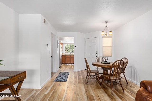 dining room with light hardwood / wood-style floors and a chandelier