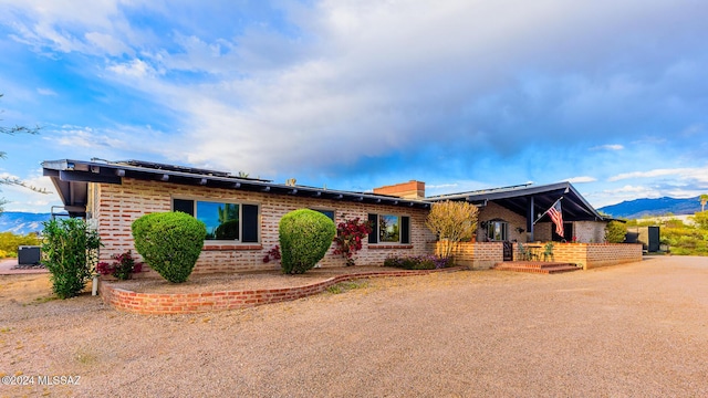 single story home with central air condition unit, a mountain view, and solar panels