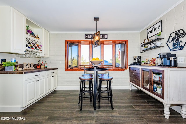 bar featuring decorative light fixtures, white cabinetry, dark wood-type flooring, and brick wall