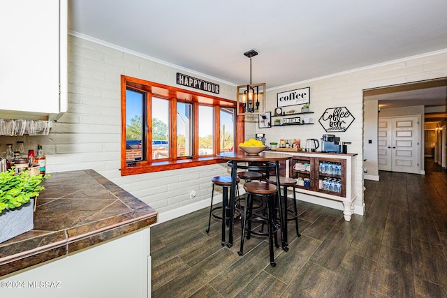 dining area featuring brick wall, dark hardwood / wood-style floors, and ornamental molding