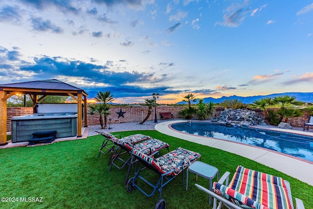 pool at dusk featuring a gazebo, a yard, and a hot tub