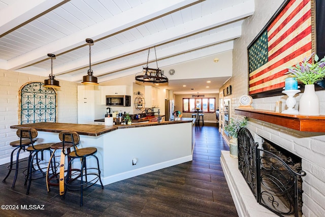 kitchen featuring hanging light fixtures, lofted ceiling with beams, dark hardwood / wood-style floors, kitchen peninsula, and a breakfast bar area