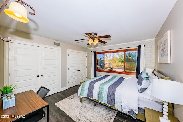 bedroom featuring multiple closets, ceiling fan, and dark hardwood / wood-style floors