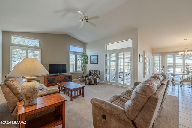 living room with ceiling fan with notable chandelier, a wealth of natural light, and vaulted ceiling