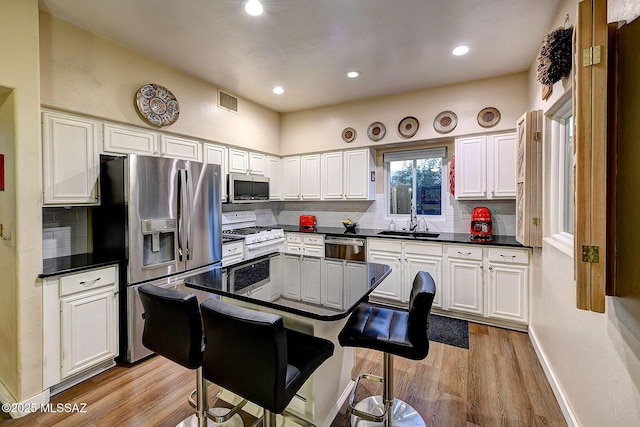 kitchen featuring tasteful backsplash, white cabinetry, sink, and stainless steel appliances