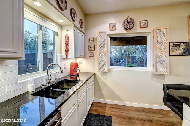 kitchen with backsplash, sink, white cabinets, and hardwood / wood-style floors