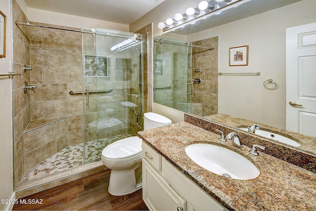 bathroom with hardwood / wood-style floors, toilet, an enclosed shower, and vanity