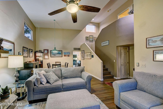 living room with ceiling fan, dark wood-type flooring, and a high ceiling