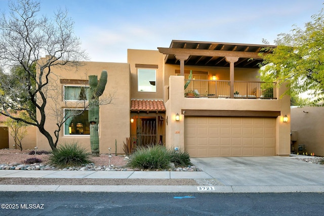 pueblo-style home featuring a garage and a balcony