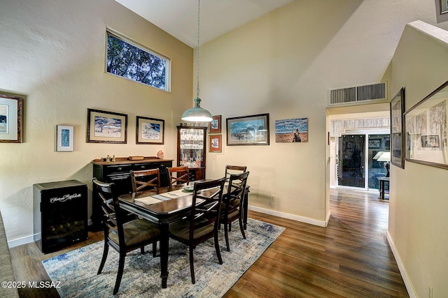 dining space featuring a towering ceiling and dark hardwood / wood-style flooring