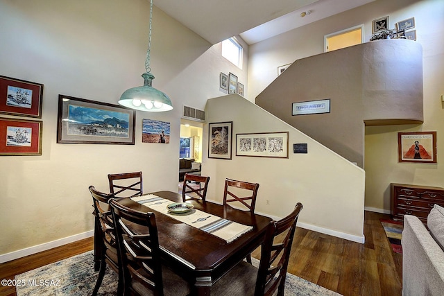 dining space featuring dark hardwood / wood-style flooring and a towering ceiling