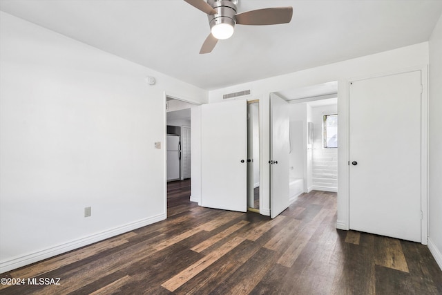 unfurnished bedroom with ceiling fan, dark hardwood / wood-style floors, white refrigerator, and connected bathroom