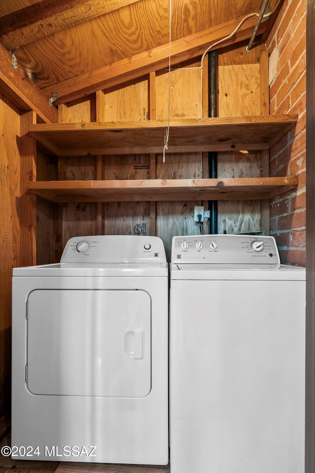 laundry room featuring wood ceiling, brick wall, and independent washer and dryer