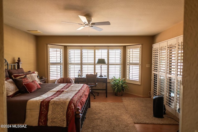 bedroom featuring wood-type flooring, a textured ceiling, and ceiling fan