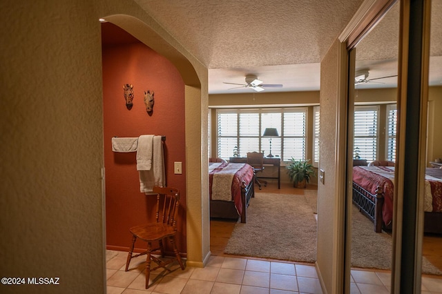 bedroom featuring ceiling fan, light tile patterned flooring, and a textured ceiling