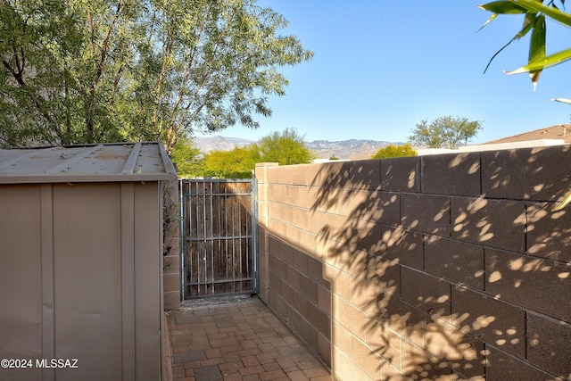 view of gate featuring a mountain view and a storage unit