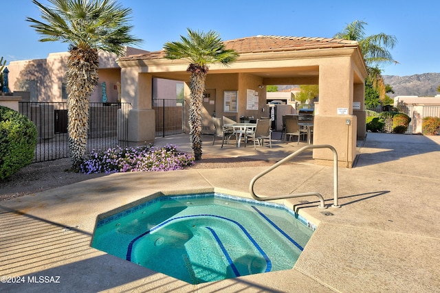 view of pool featuring a mountain view, a patio, and a hot tub